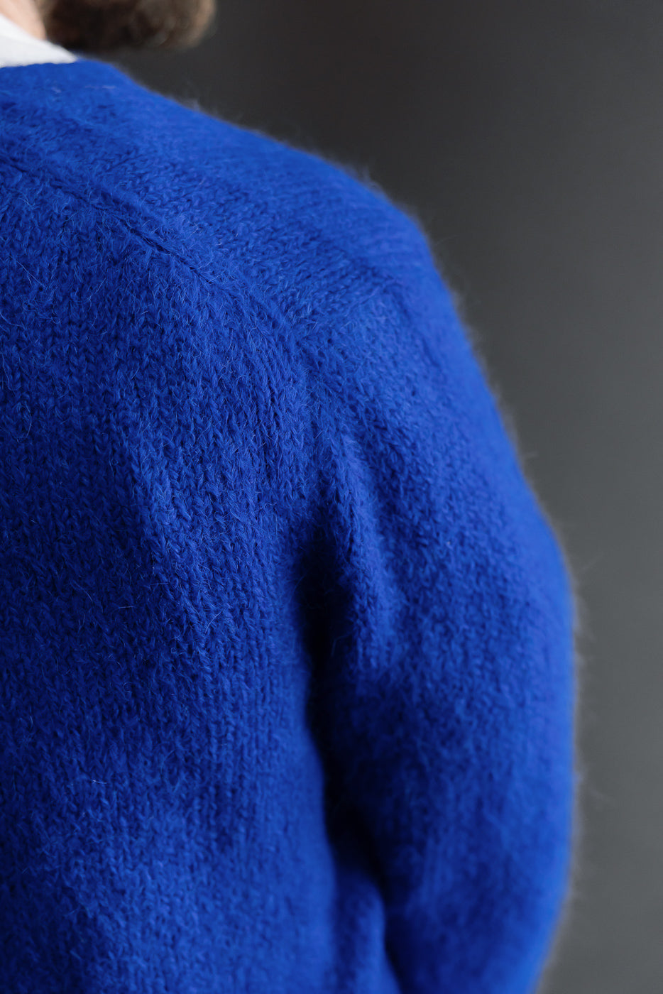 Close-up of the back shoulder and sleeve texture of a blue fuzzy mohair sweater.