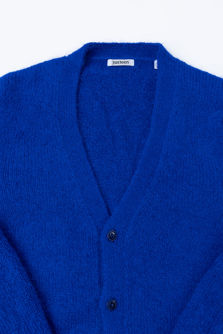 Close-up front view of a blue knit cardigan showing button details and soft fabric texture.