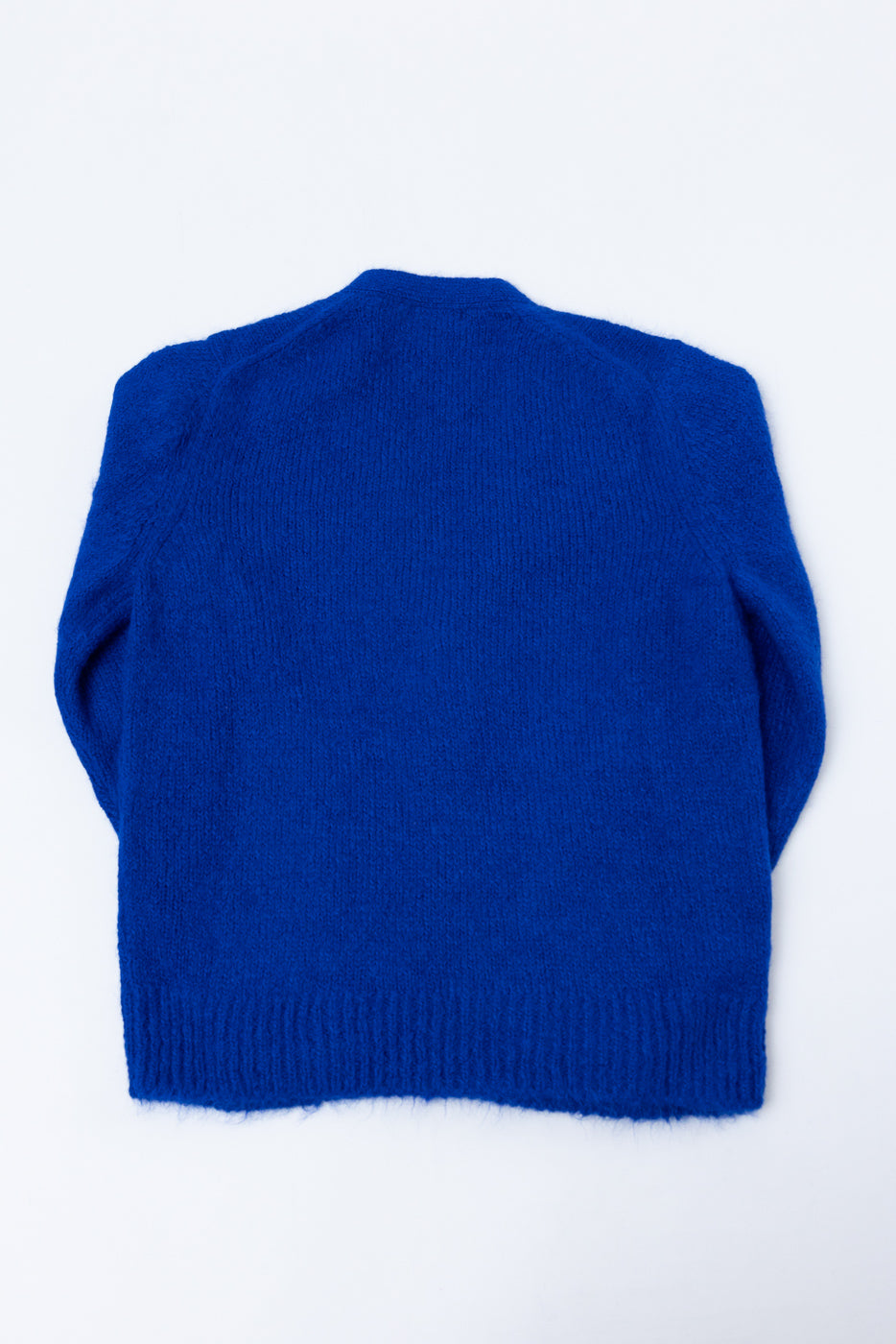 Back view flat lay of a blue knit sweater with ribbed hem and cuffs.