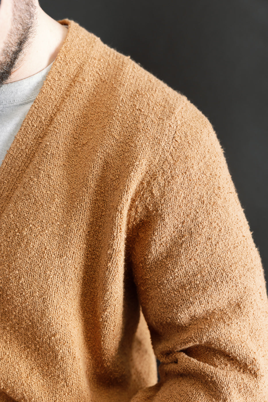 Close-up of male model's right shoulder in ochre boucle cardigan, showing textured knit fabric and relaxed fit. Model is 5'9