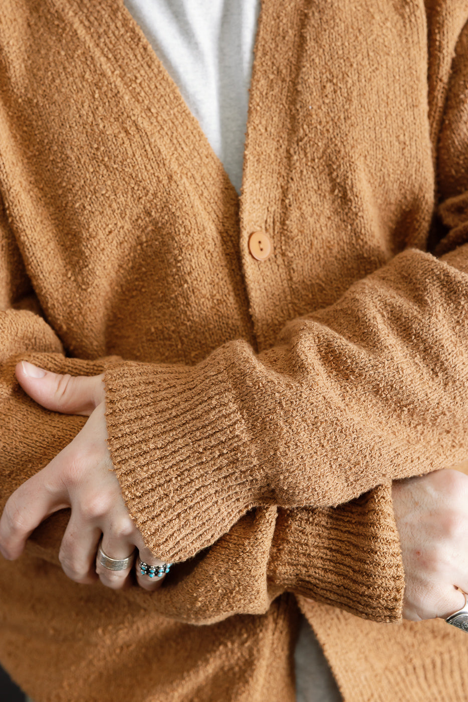 Close-up front view of ochre boucle cardigan on male model, showing button, texture, ribbed cuffs.