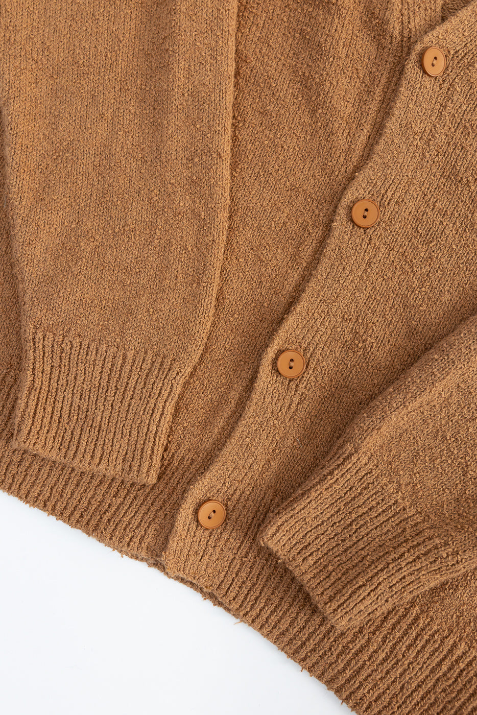 Close-up of ochre boucle cardigan front, showing button details, textured knit, ribbed hem and cuffs.