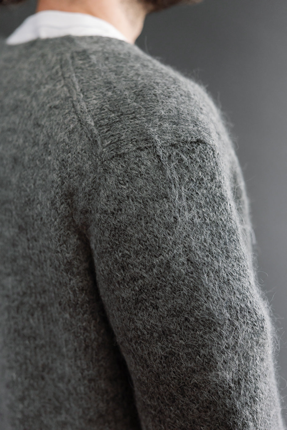 Close-up of the back and shoulder of a grey knit sweater on a 5'9