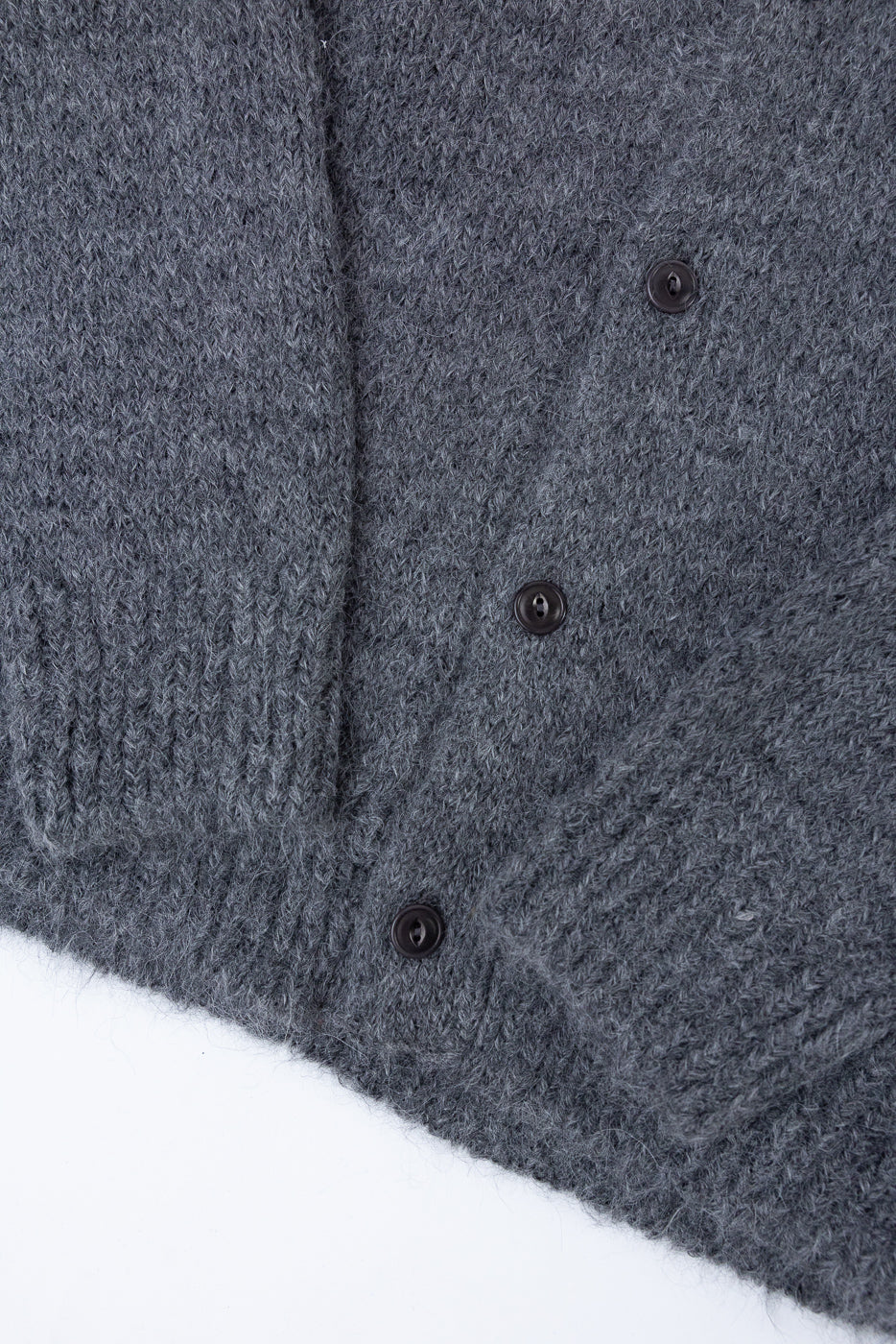 Close-up of the front of a grey knit cardigan showing button details and fabric texture.