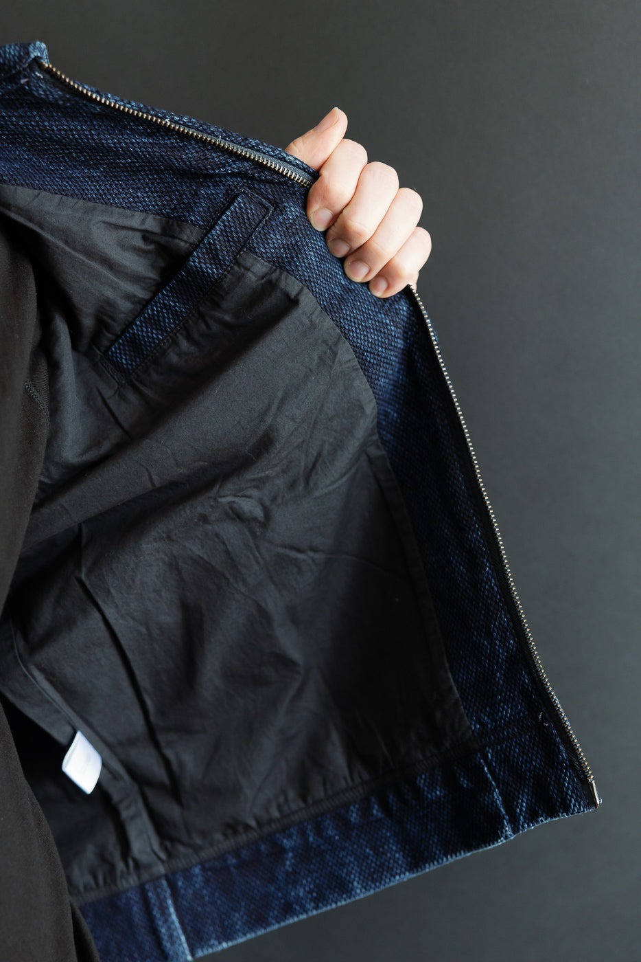 Close-up of the interior lining and textured blue fabric of a jacket, showing the inner side.