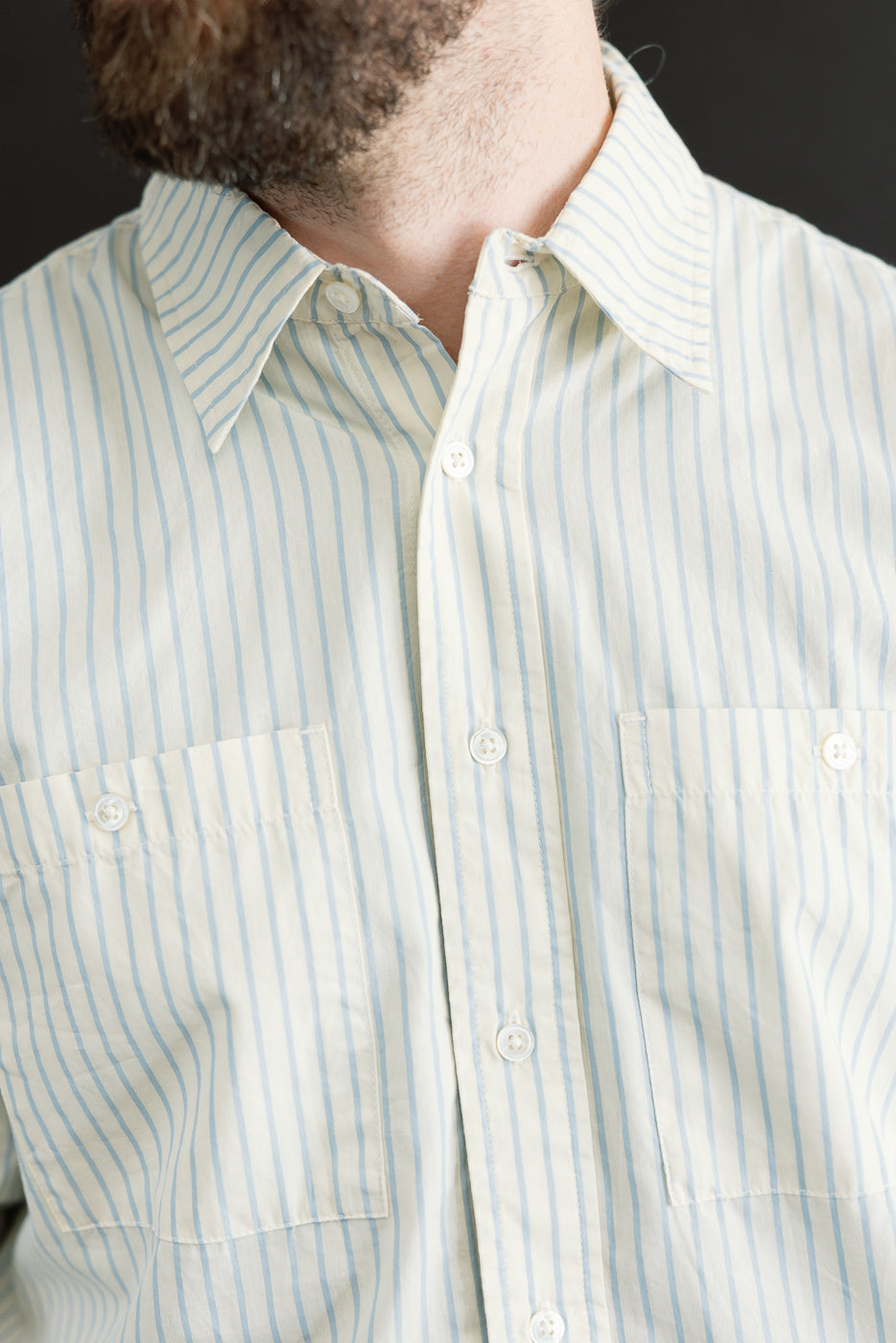 Close-up front view of a light blue and white striped button-down shirt showing collar and pockets.