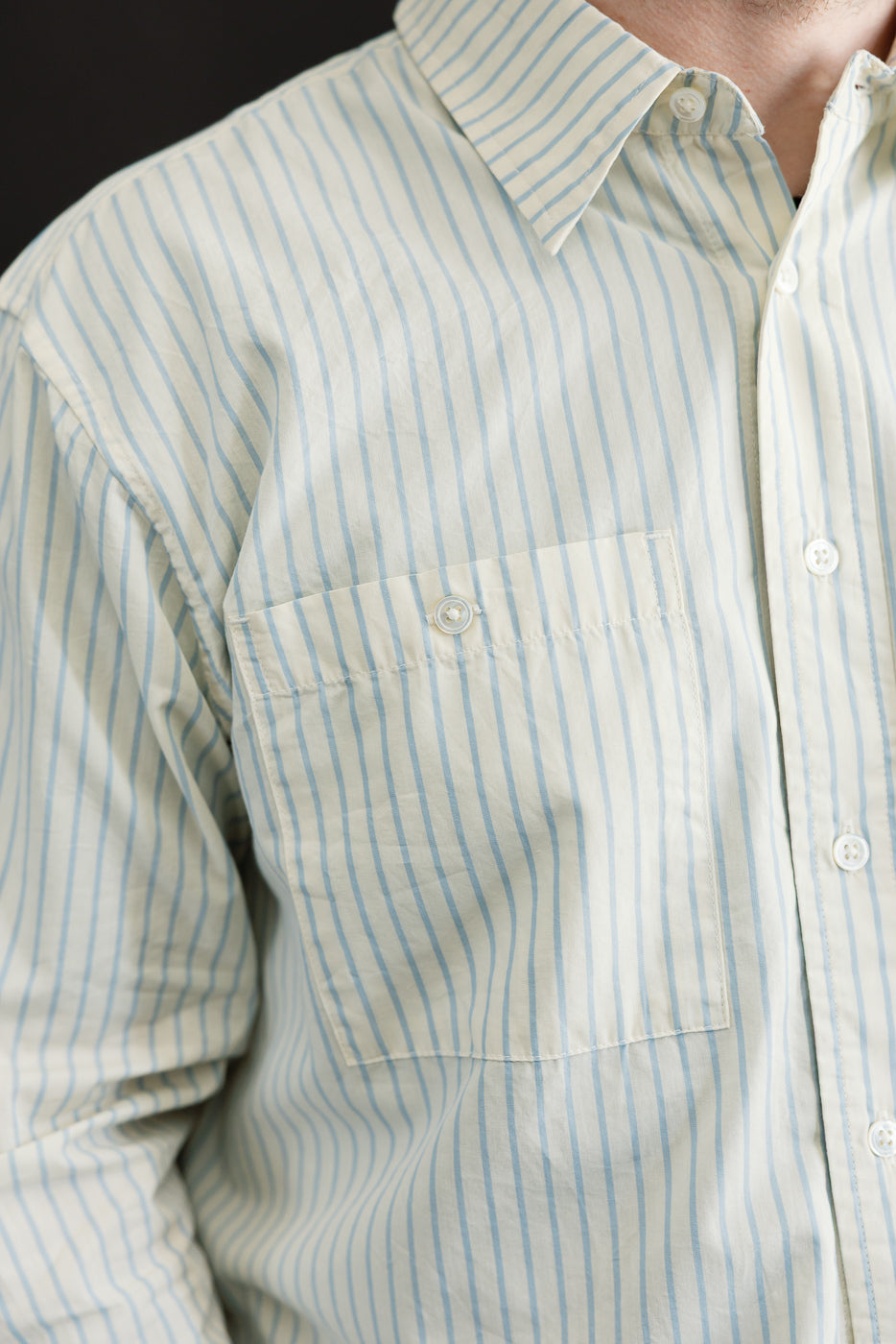 Close-up front view of a light blue and white striped button-down shirt showing the chest pocket.