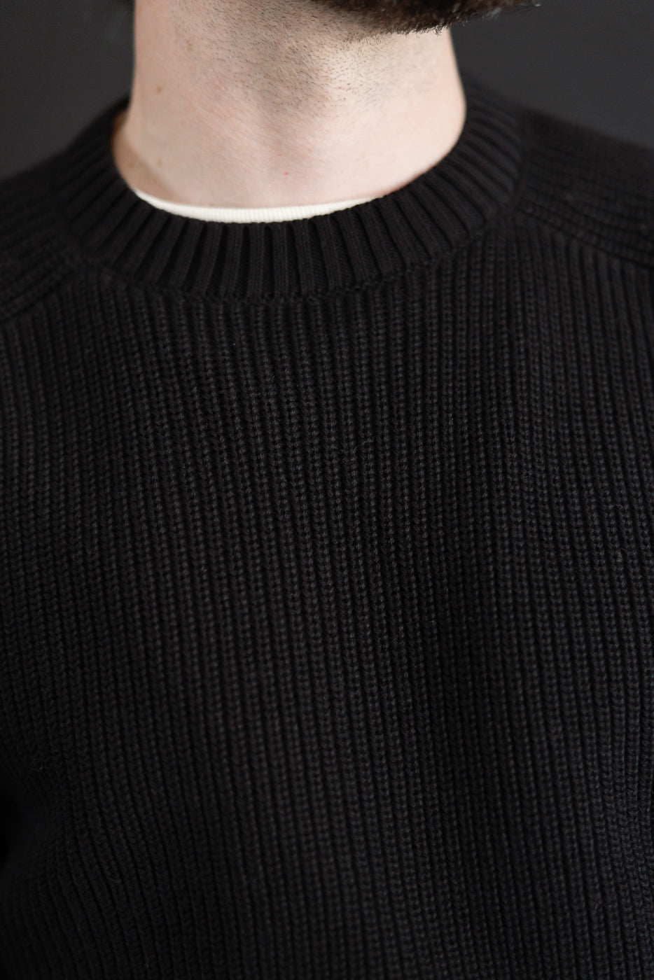 Close-up front view of black ribbed knit sweater on male model, 5'9