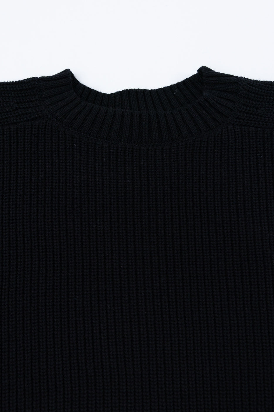 Close-up of the front neckline and ribbed collar of a black knit sweater.