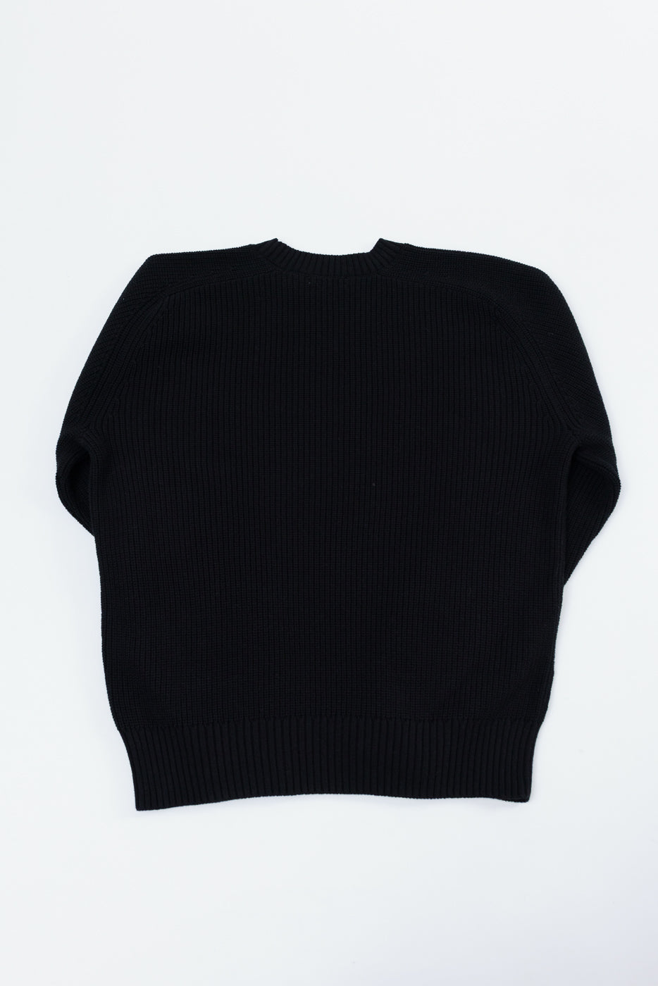 Back view flat lay of a black ribbed knit sweater.