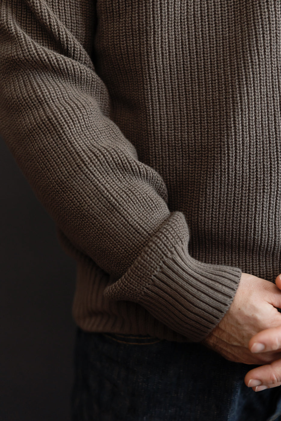 Close-up of the front side showing the ribbed texture and sleeve of a brown knit sweater.
