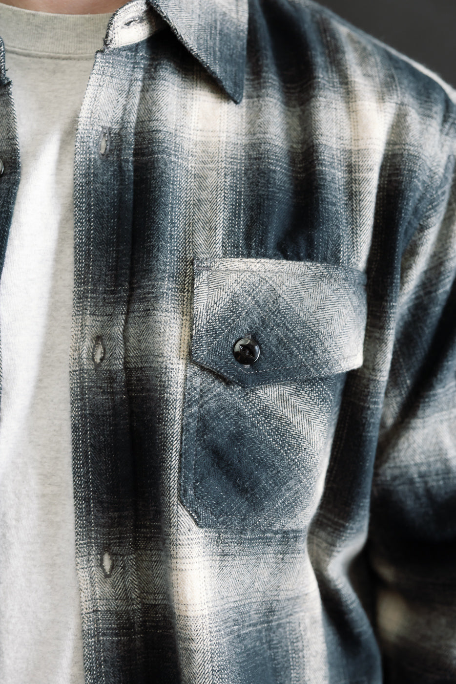 Close-up of men's black ombre plaid flannel shirt, front chest pocket, button detail, left side view