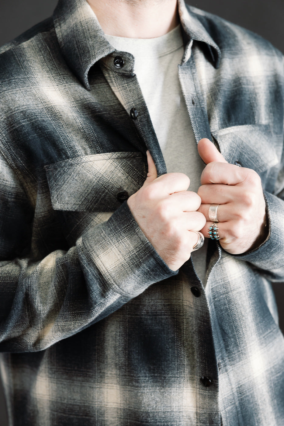 Close-up front view of black ombre plaid flannel shirt on male model, chest details visible, showing buttons, chest pocket, and collar. Model is 5'9