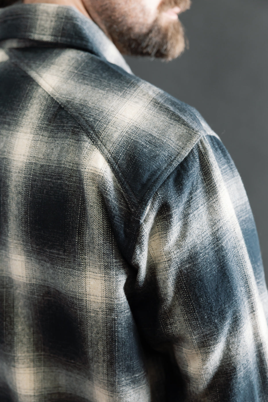 Close-up of back shoulder and collar detail, black ombre plaid flannel on male model, 5'9
