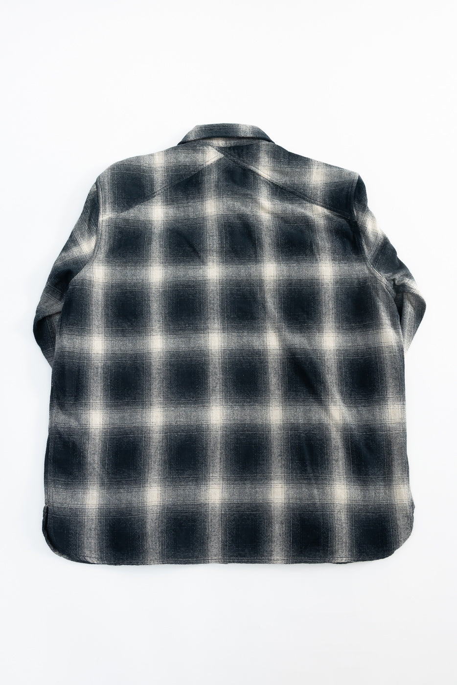 Flat lay of black ombre plaid flannel shirt, back view showing fabric texture and yoke detail.