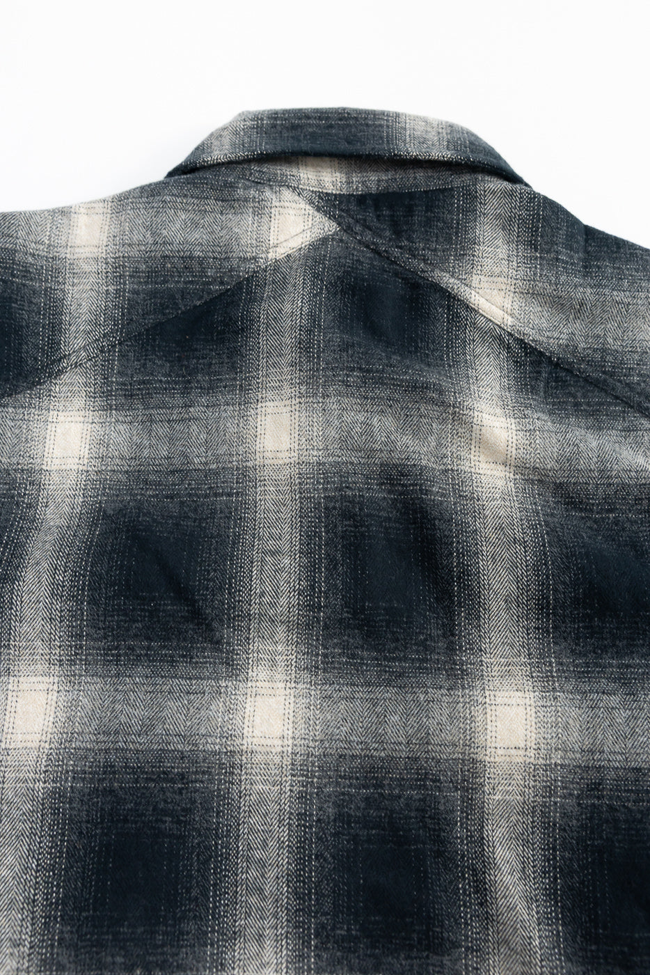 Close-up of the back yoke and collar of black ombre plaid flannel shirt showing fabric texture.