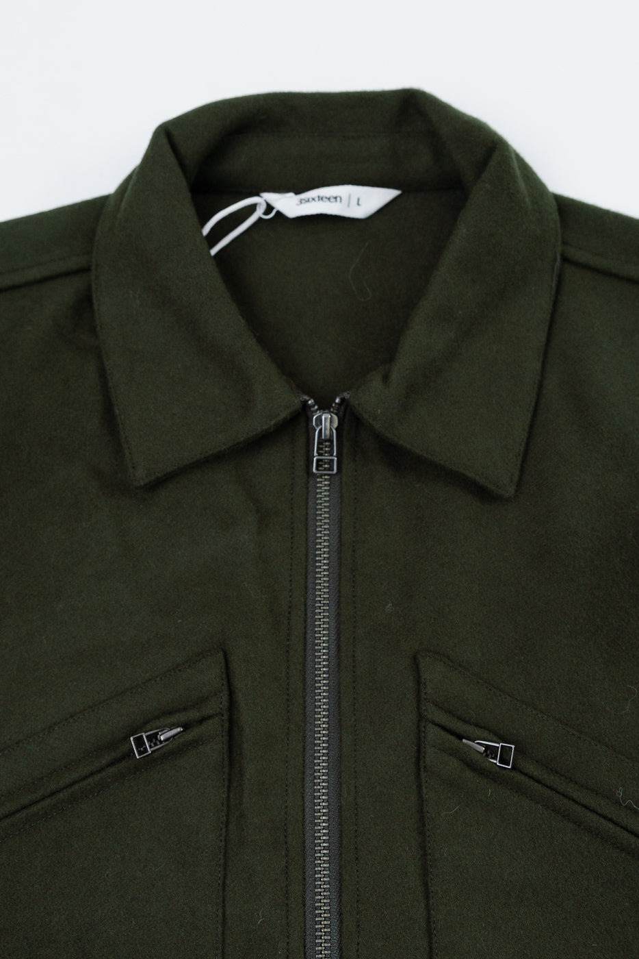 Close-up front view of a dark green textured fabric jacket showing the collar and zipper detail.