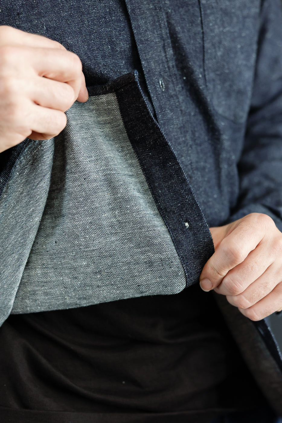 Close-up of the interior grey heather fabric lining and front placket of a navy denim shirt.