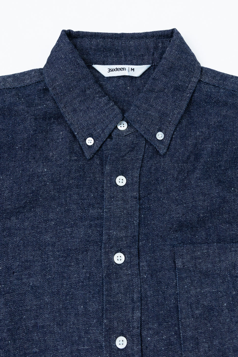 Close-up front view of a navy blue textured button-down shirt showing collar and button details.