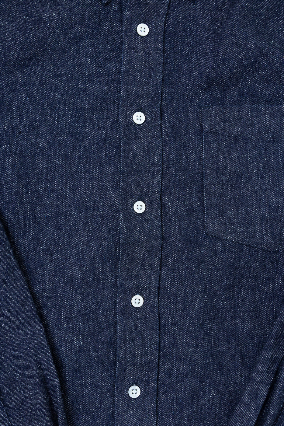 Close-up front view of navy blue textured fabric shirt with white buttons and chest pocket.