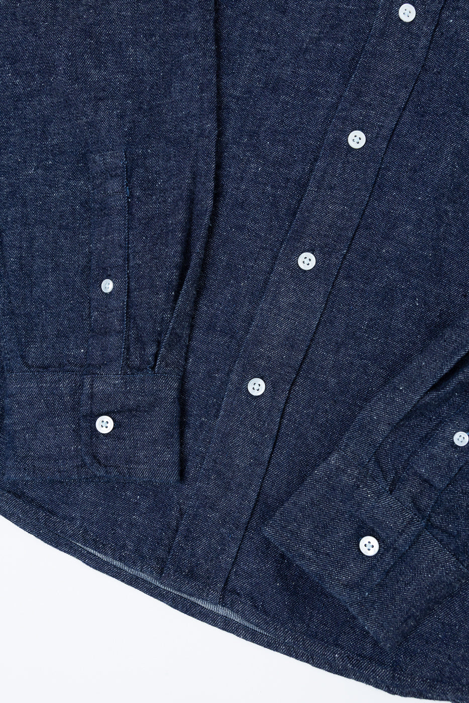 Close-up front view of navy blue denim shirt showing fabric texture and white buttons.