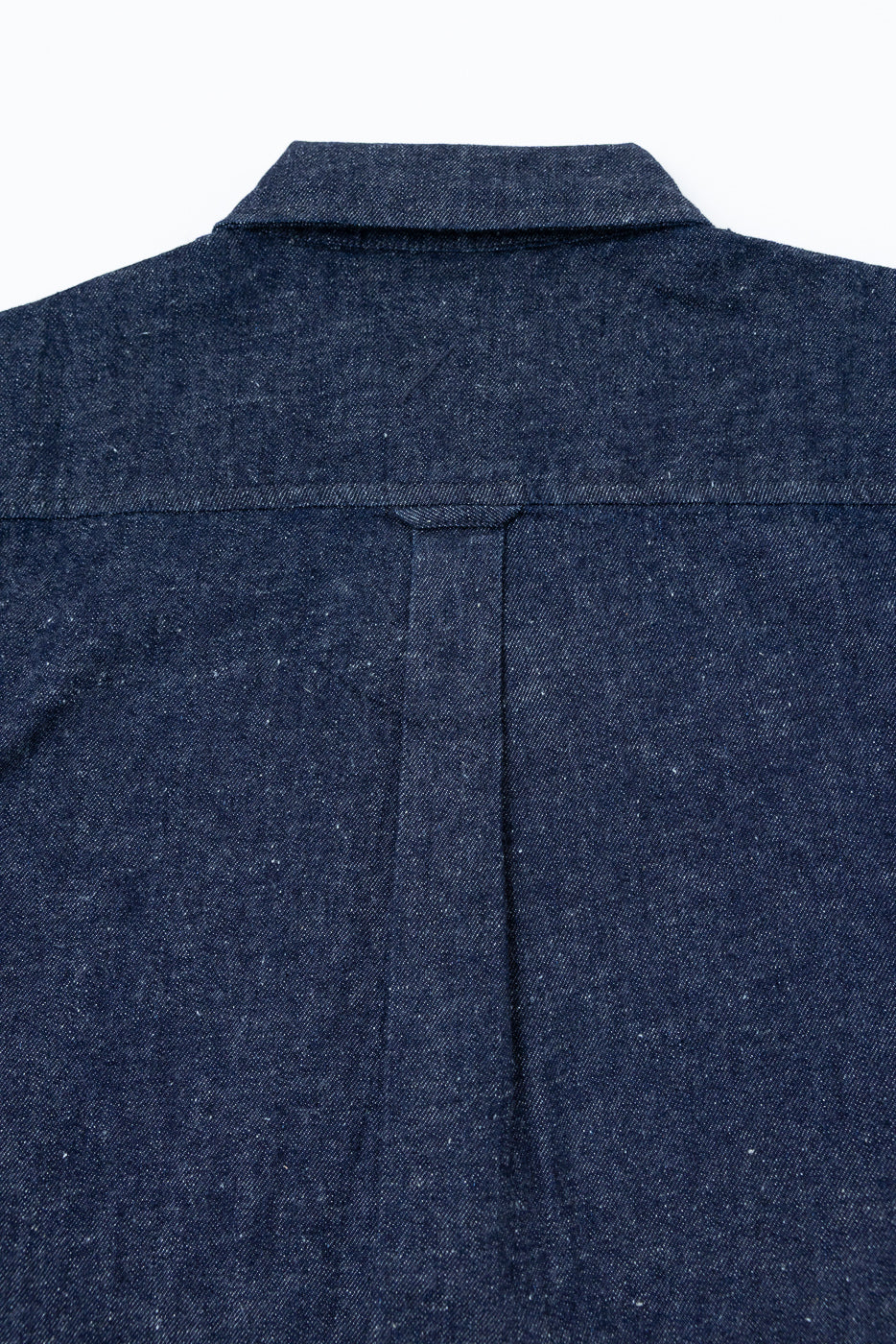 Close-up back view of a navy blue denim shirt showing the collar and yoke detail.