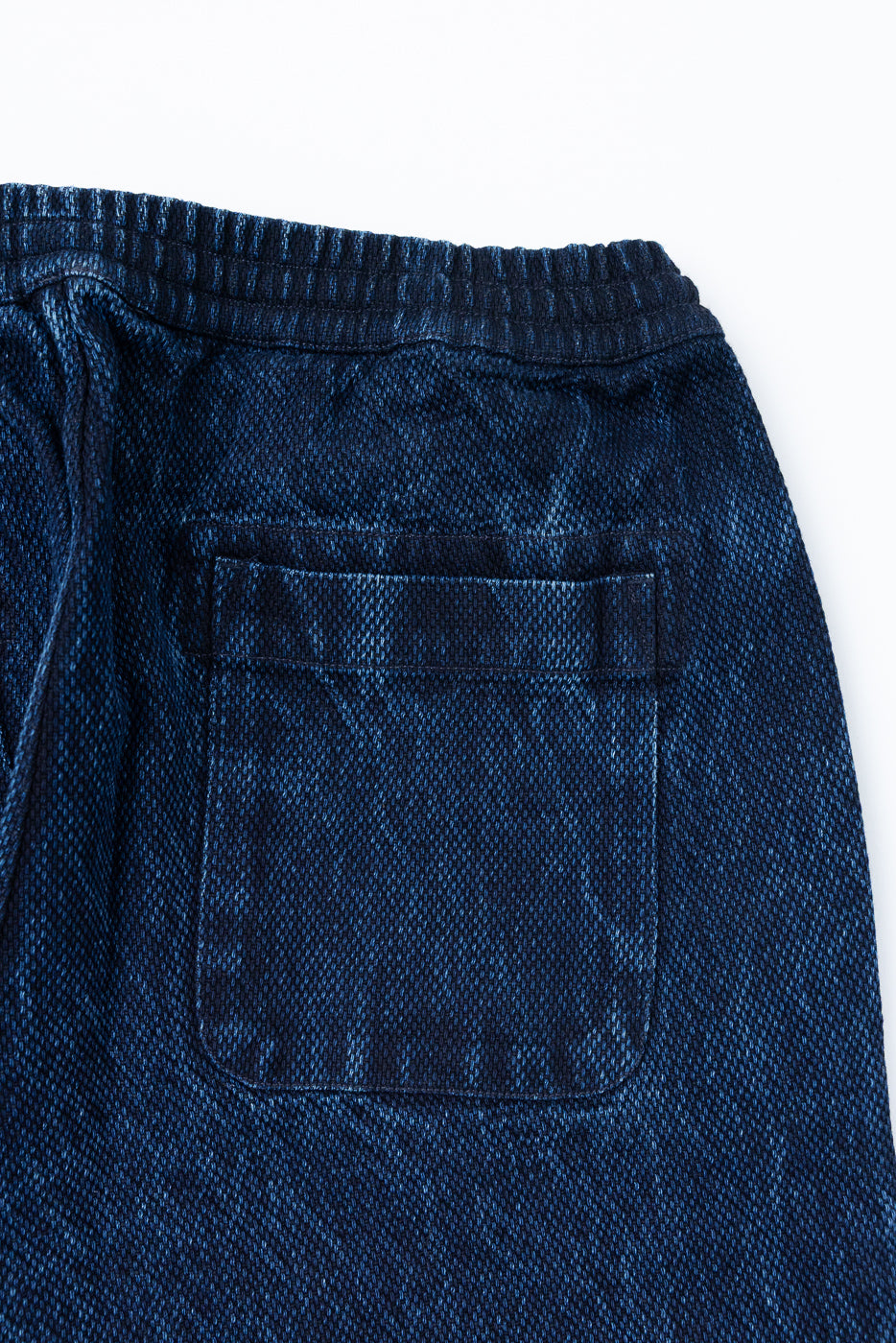 Close-up of the back view showing the rear pocket and waistband of blue denim shorts.