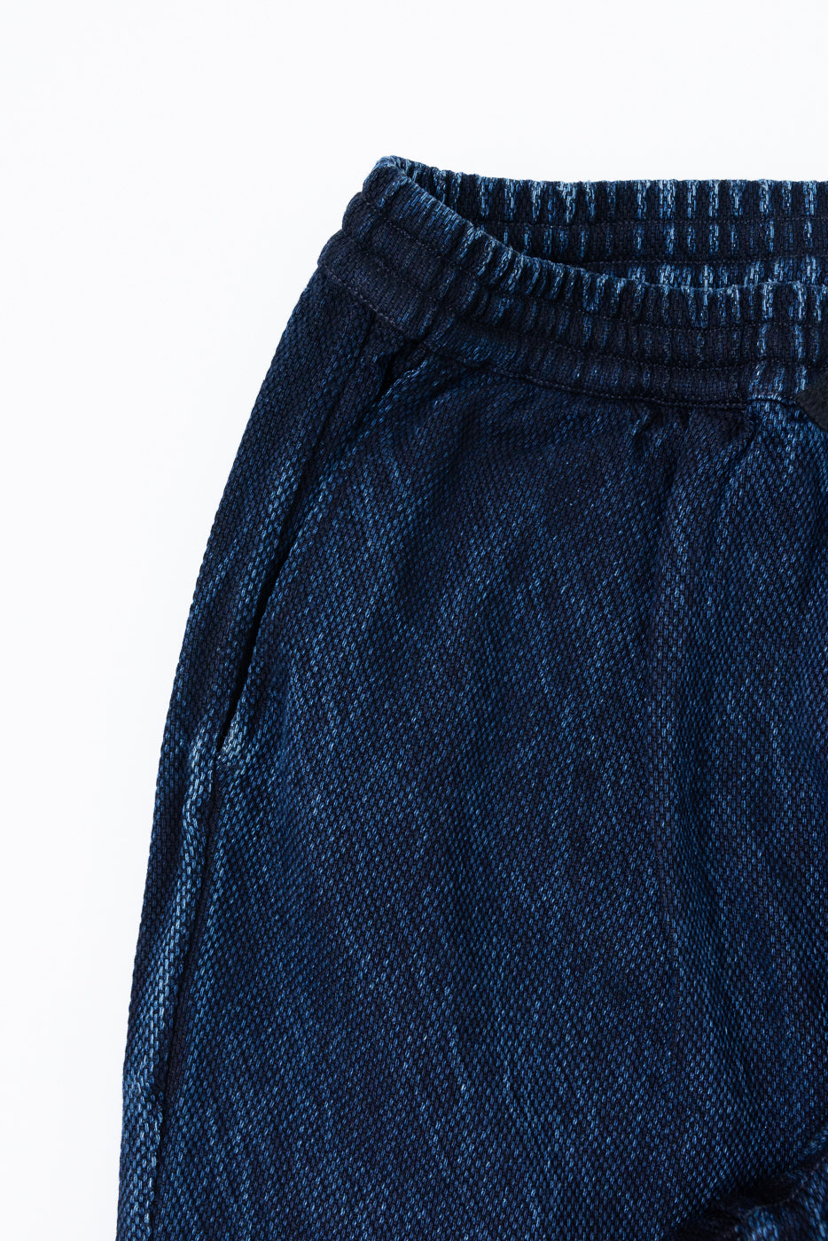 Close-up of the elastic waistband and side seam of navy blue textured lounge pants.