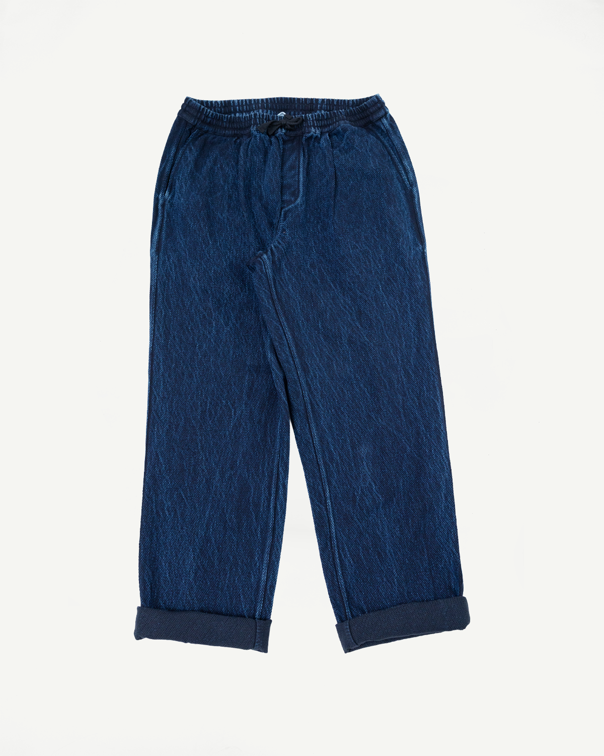 Front view flat lay of blue denim drawstring trousers with cuffed hems.