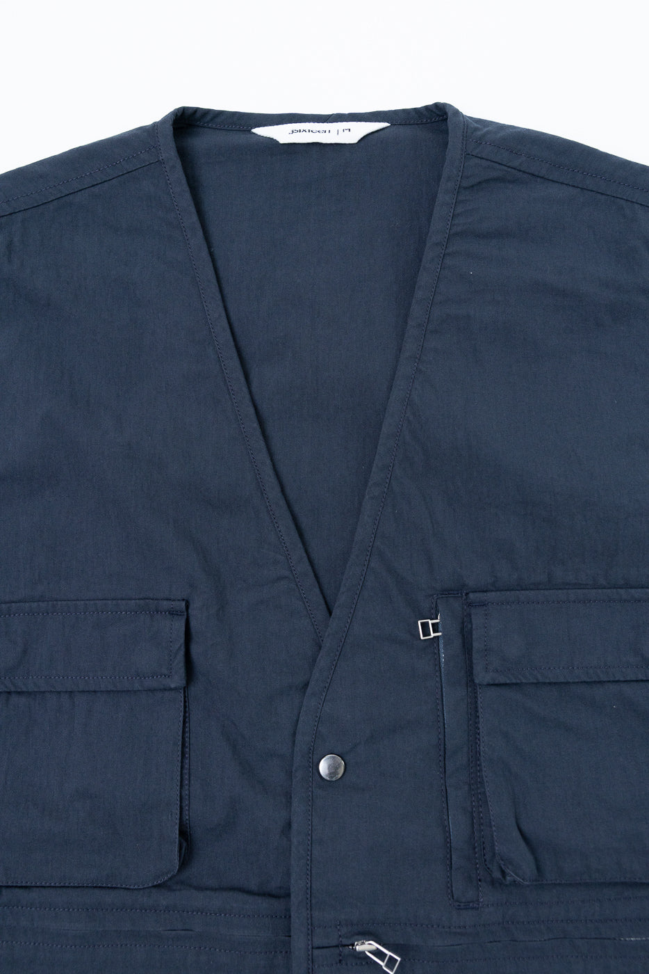 Close-up front view of navy blue utility vest showing fabric texture and silver metal hardware.