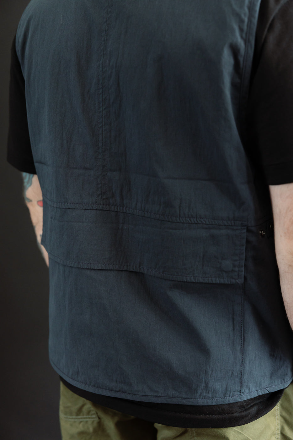 Back view close-up of a dark navy utility vest on a male model, 5'9