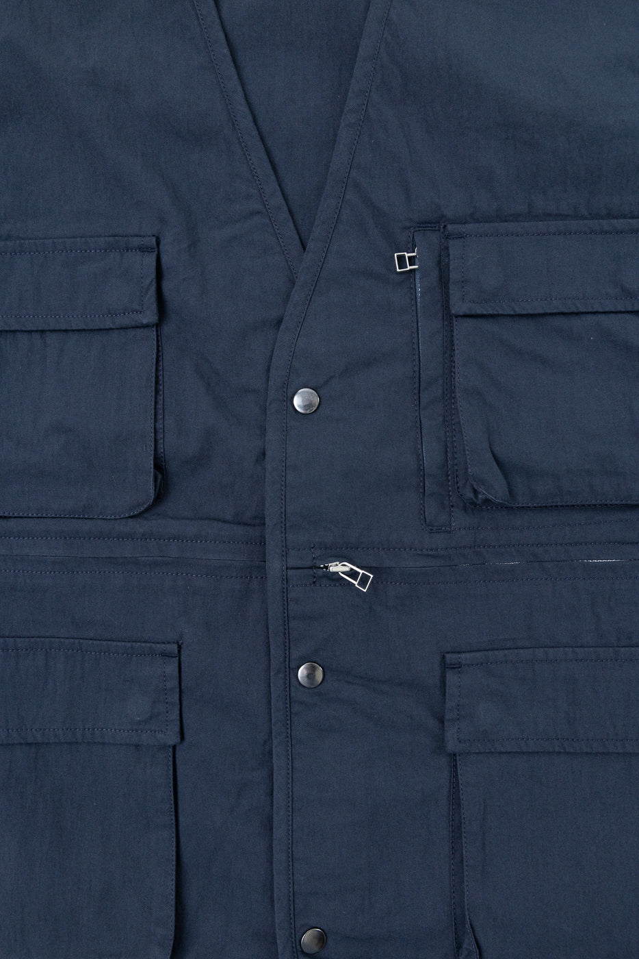 Close-up front view of navy utility vest showing snap buttons and pocket details.