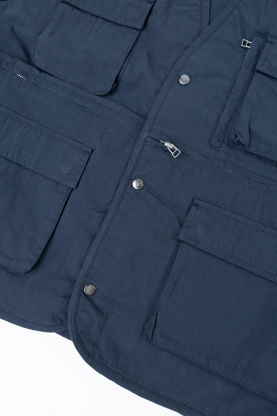 Close-up front view of a navy blue utility vest showing fabric texture, snap buttons, and pockets.