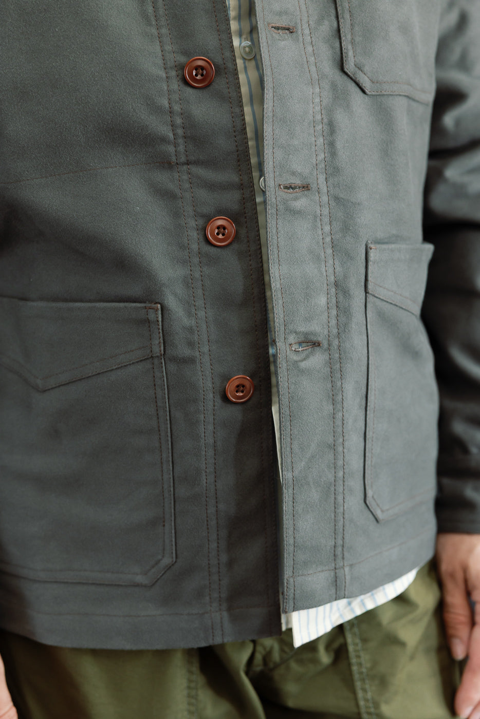 Close-up front view of a grey utility jacket showing brown buttons and fabric texture.