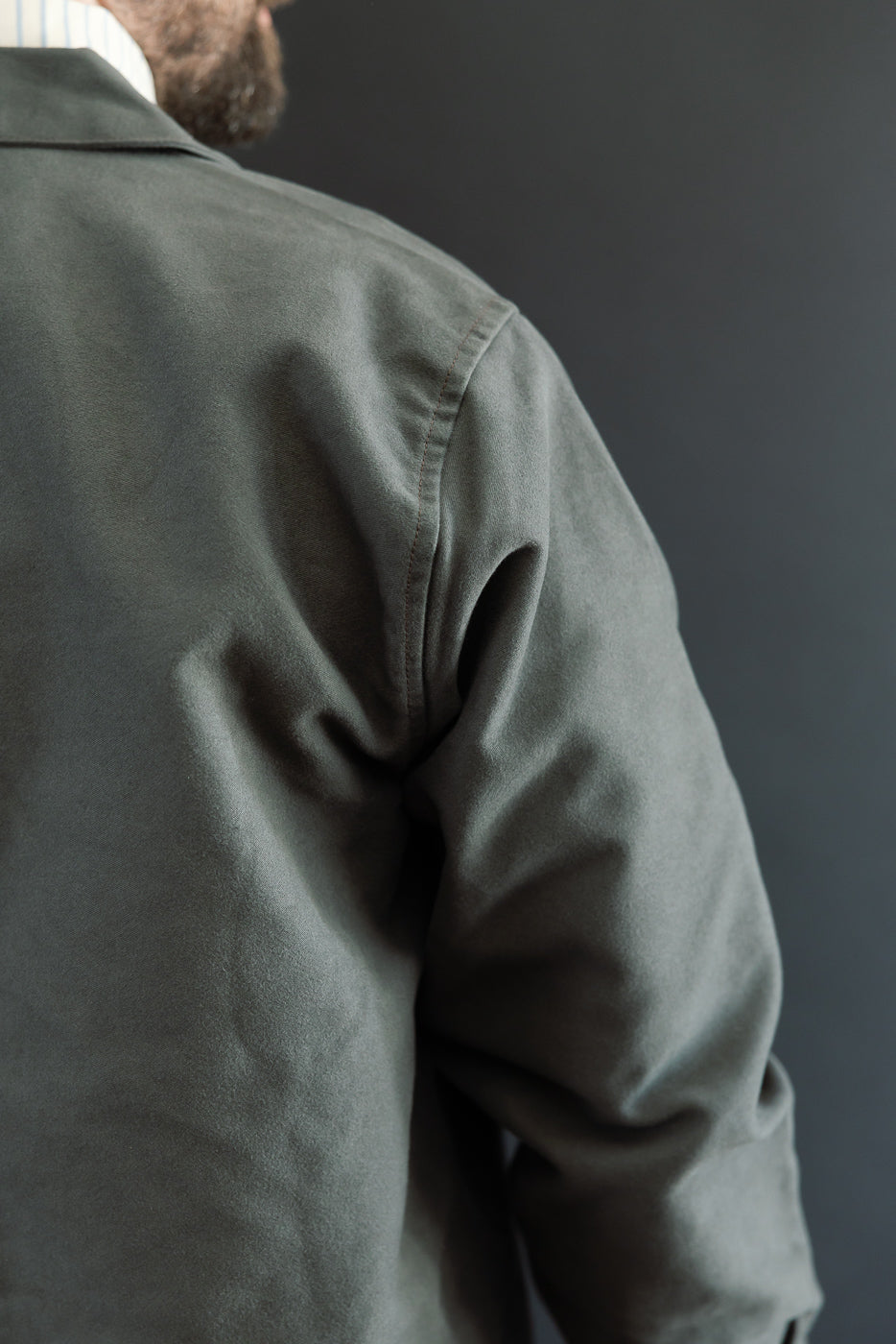 Close-up of the back and right sleeve of a grey cotton jacket on a 5'9