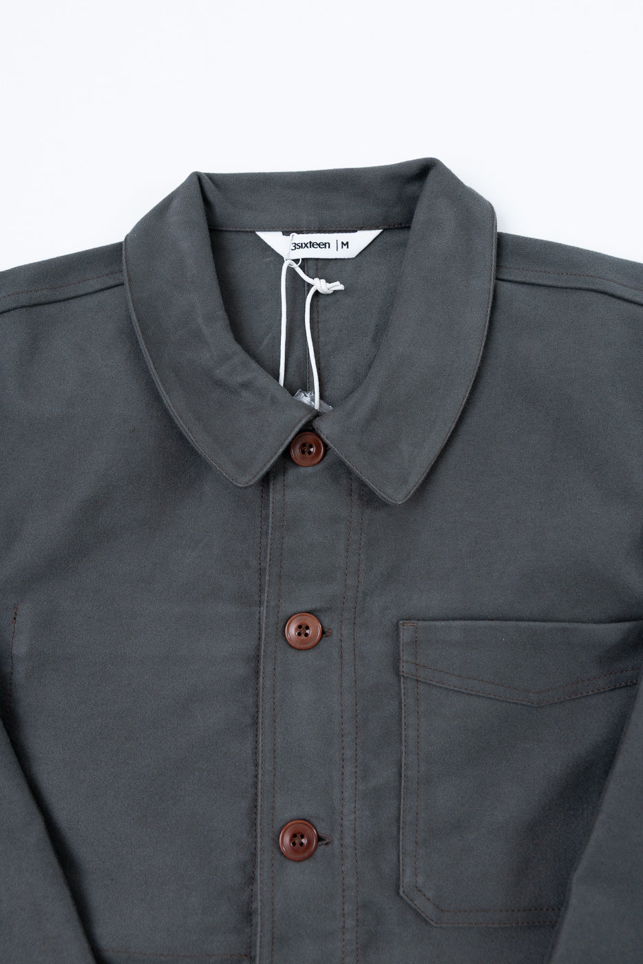 Close-up front view of a grey button-up shirt showing collar, brown buttons, and chest pocket.