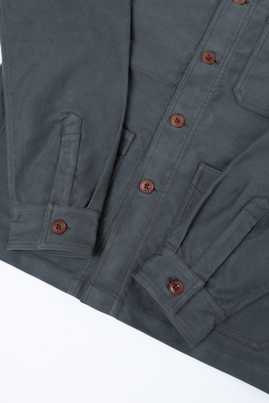 Flat lay close-up of the front of a charcoal grey button-down shirt showing cuff and button details.