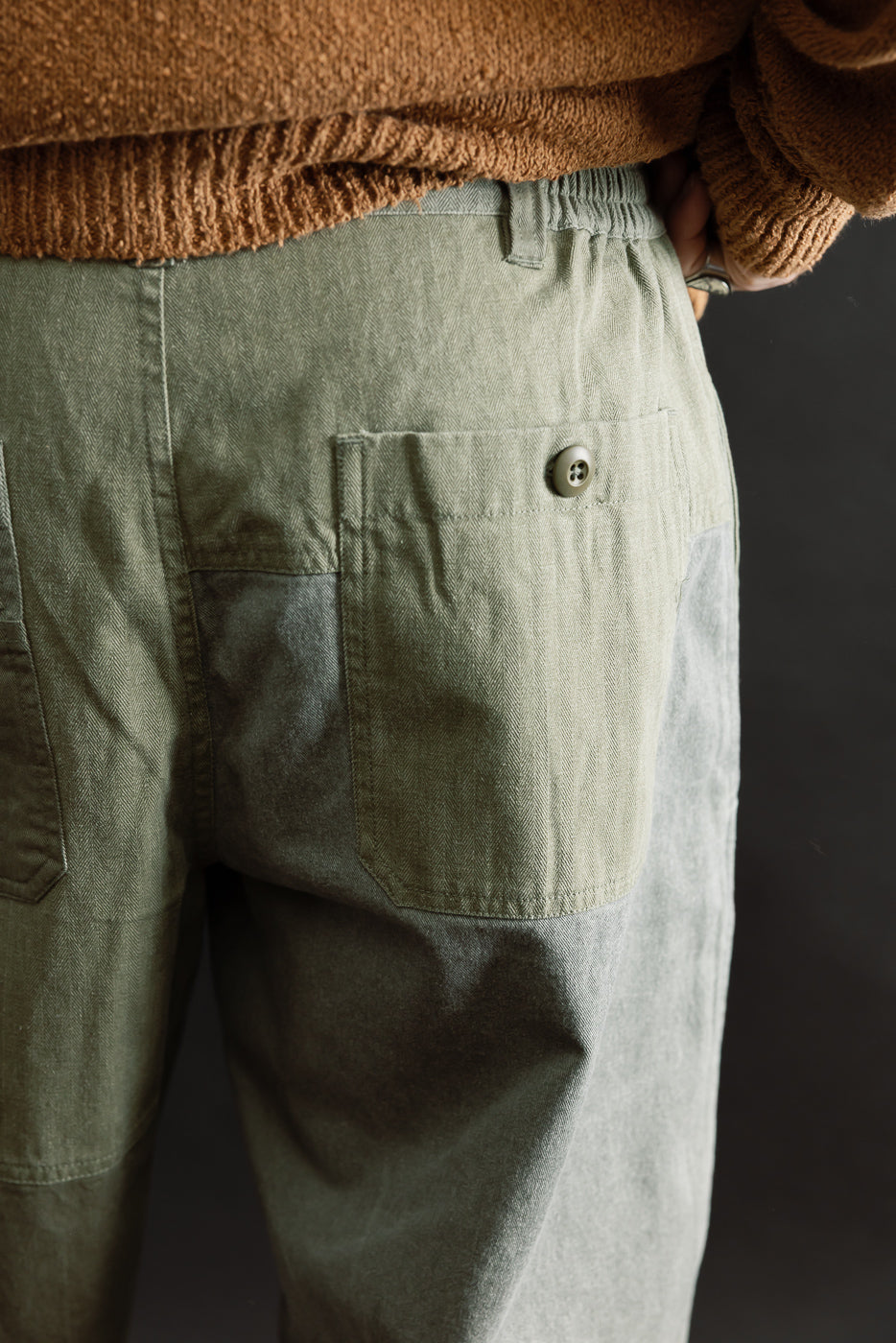Close-up of patchwork olive pant back, buttoned pocket, male model 5'9 165lbs athletic build