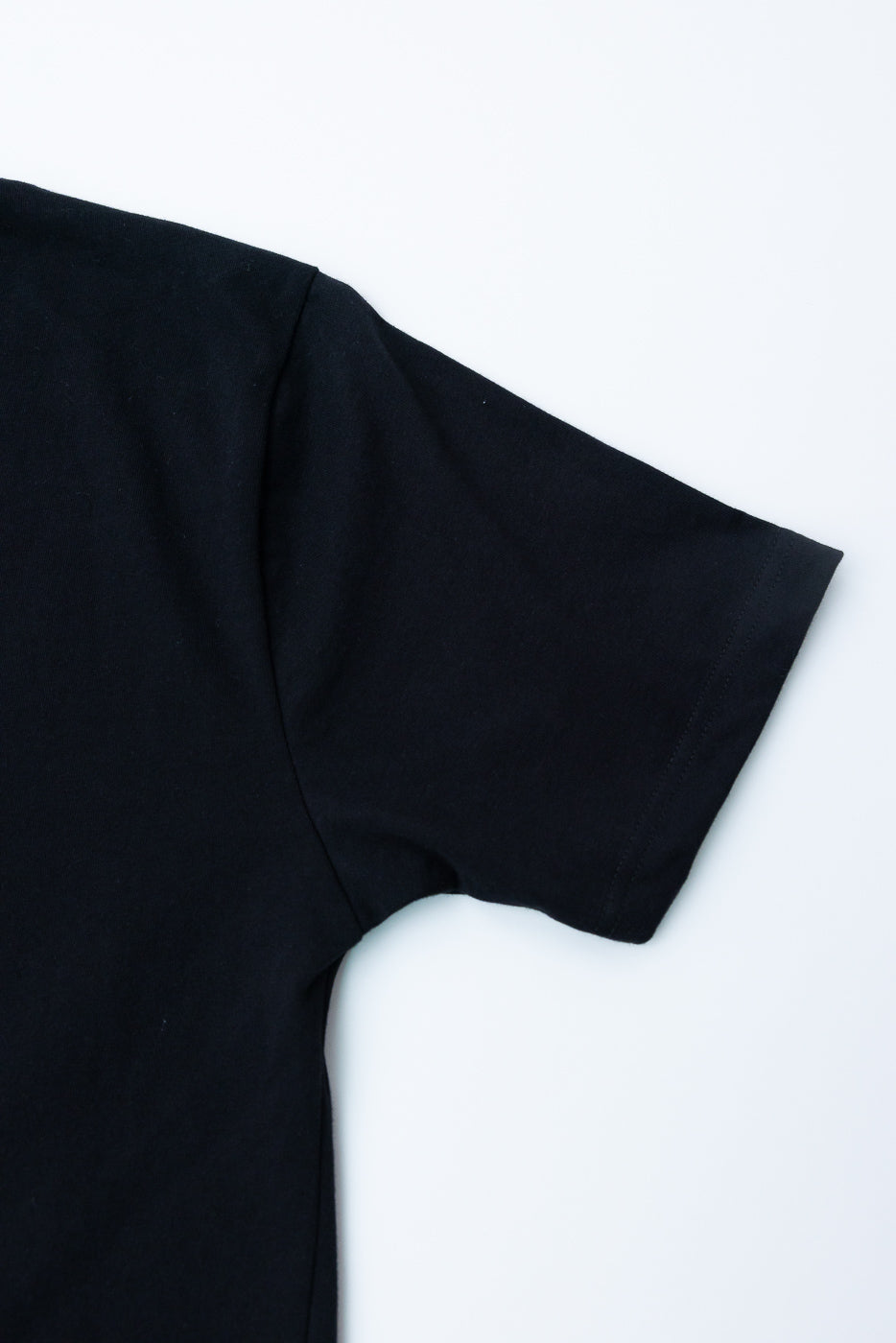 Close-up of black heavyweight boxy t-shirt, flat lay, showing right sleeve and shoulder.