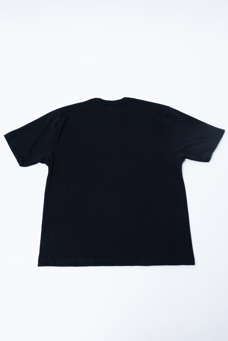 Flat lay of heavyweight boxy black t-shirt, back view, showing short sleeves and straight hem.