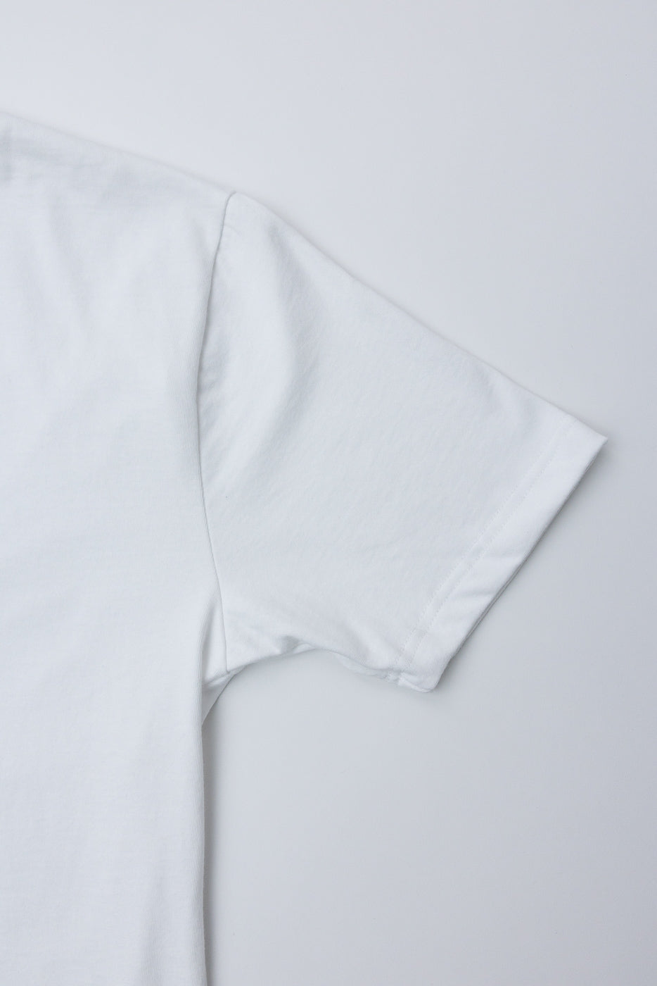 Close-up of white heavyweight boxy t-shirt right sleeve and shoulder, flat lay, front view
