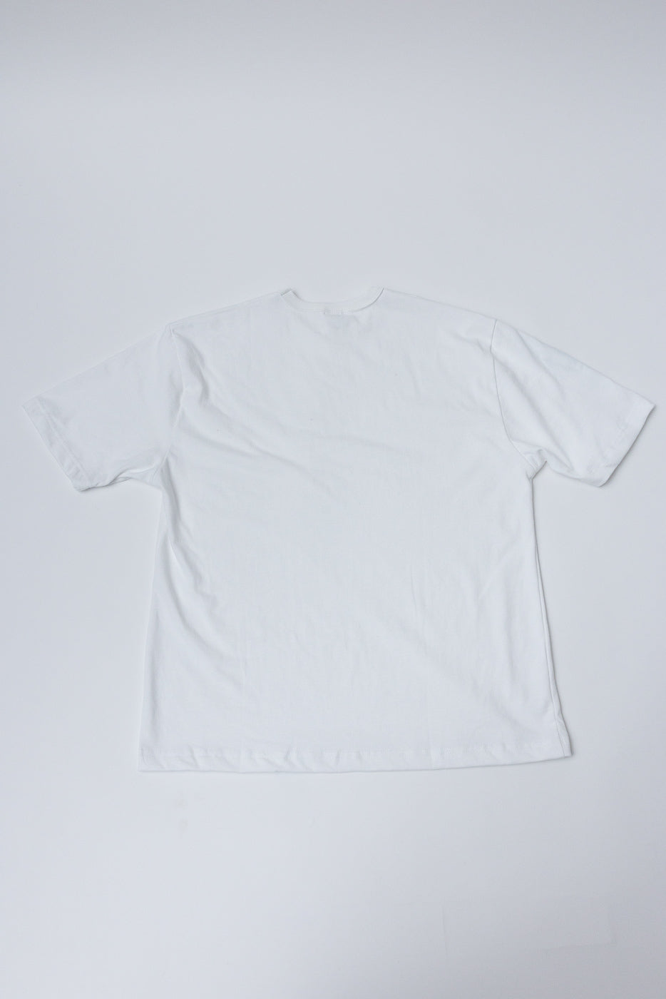 Flat lay of heavyweight boxy white t-shirt, back view, showing short sleeves and straight hem.