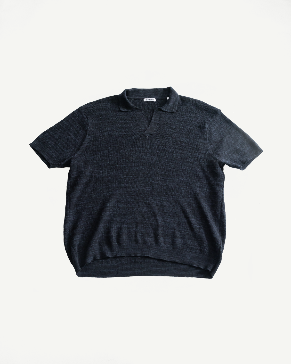 Flat lay front view of vintage black boxweave knit polo shirt, short sleeves, classic collar, textured fabric.