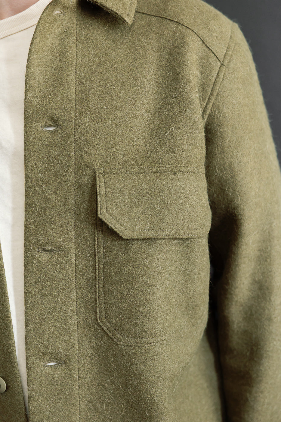 Close-up of the front left side of an olive wool jacket on a 5'9