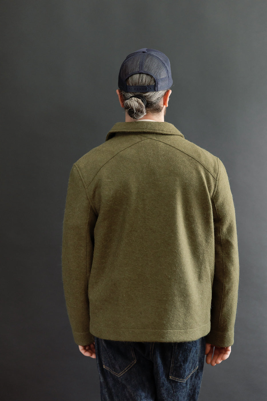 Back view of an olive green wool jacket on a male model, 5'9
