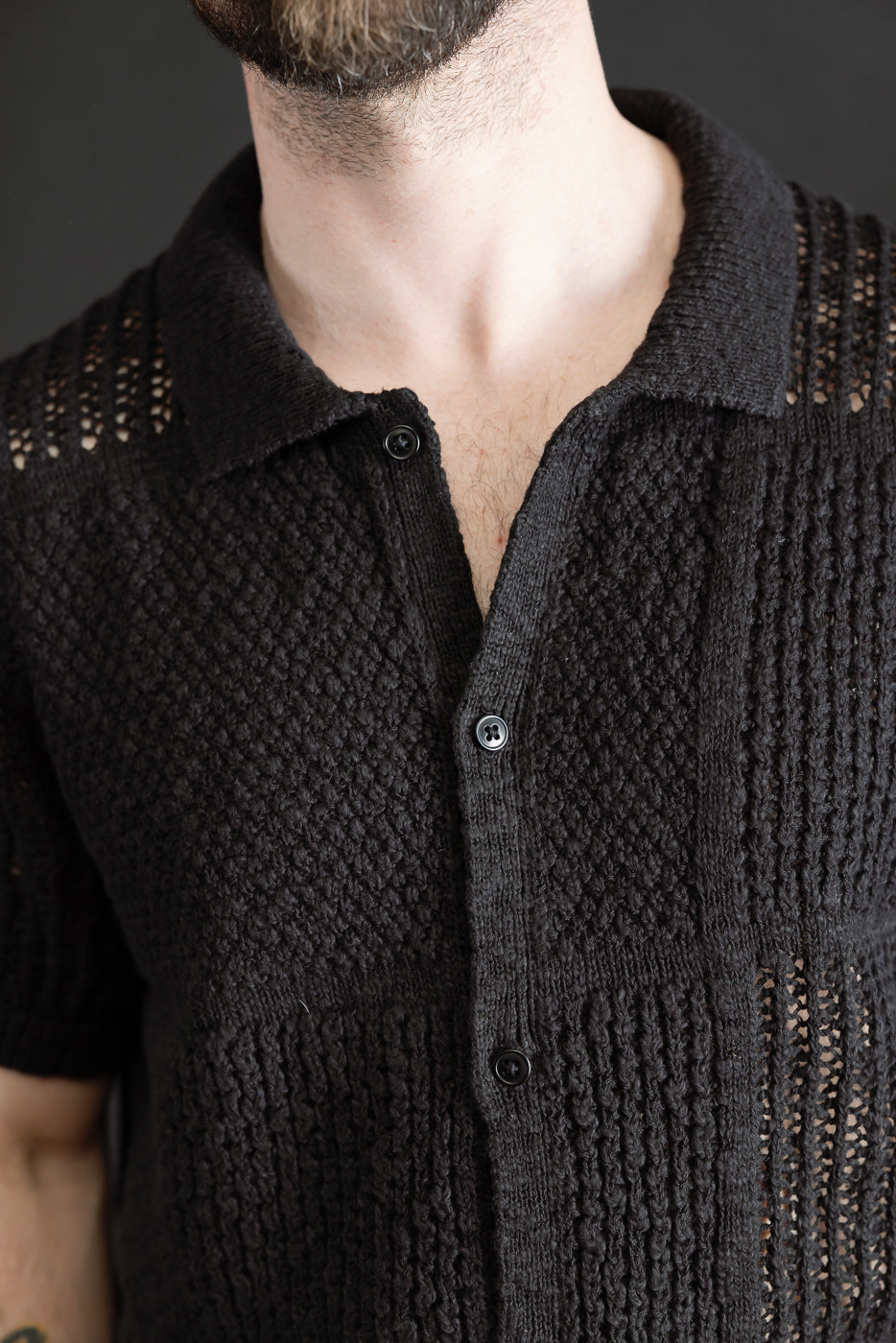 Close-up front of black short-sleeve knit shirt on male model 5'9