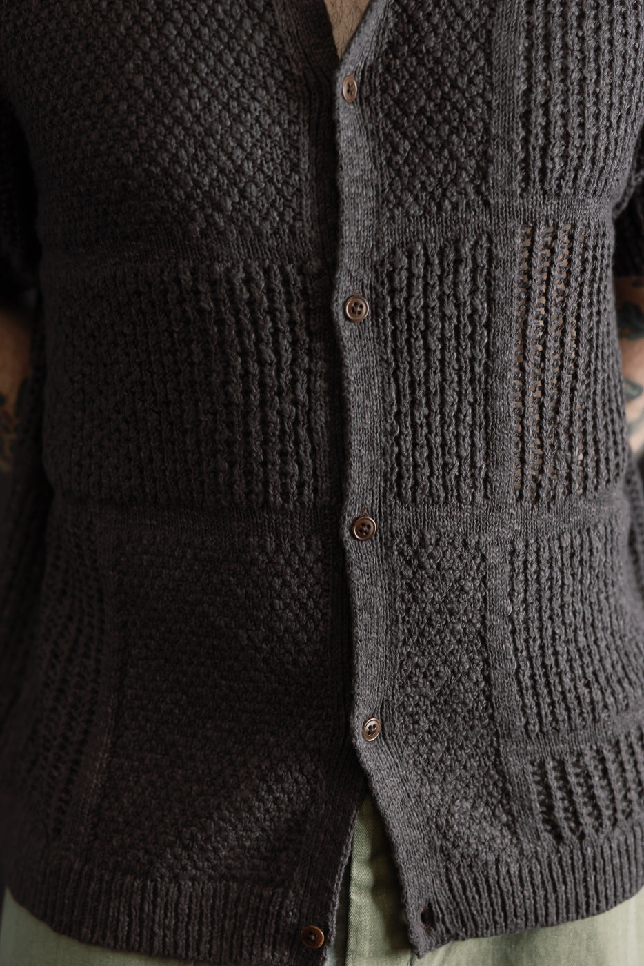 Close-up front view of men's short sleeve knit shirt in umber, brown buttons, textured pattern, male model 5'9