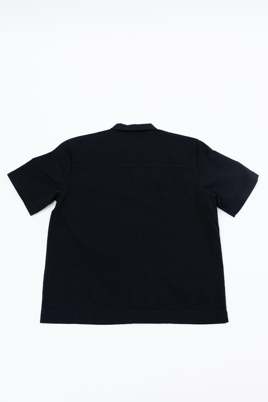 Short Sleeve Loop Shirt - Black Seersucker, displayed flat from the back, showcasing its simple design and premium cotton texture, emblematic of Dant's high-end menswear and meticulous craftsmanship.