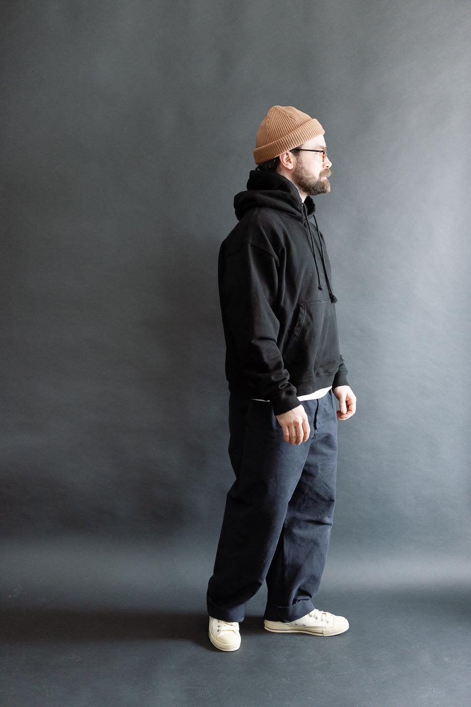 Male model 5'9 165lbs athletic build in 3sixteen ultraweight black pullover hoodie, right side full body view