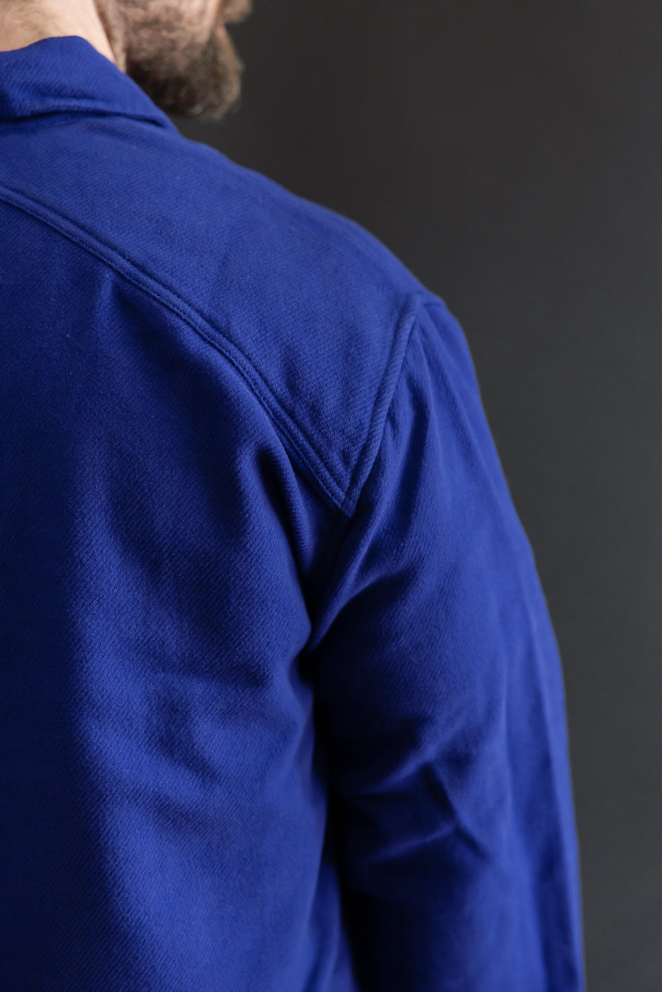 Close-up of the back and right shoulder of a blue textured fabric garment.
